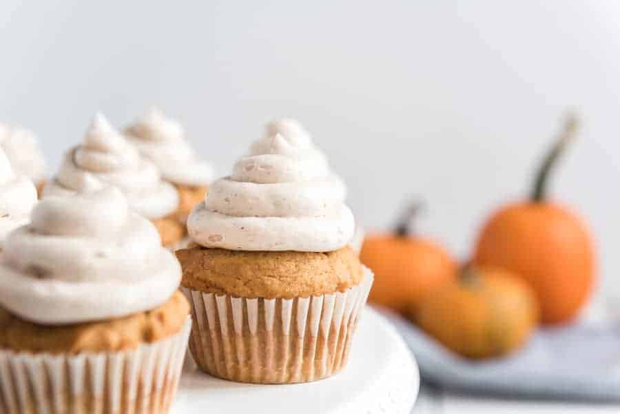 Pumpkin cupcakes with cinnamon icing on a cake stand.