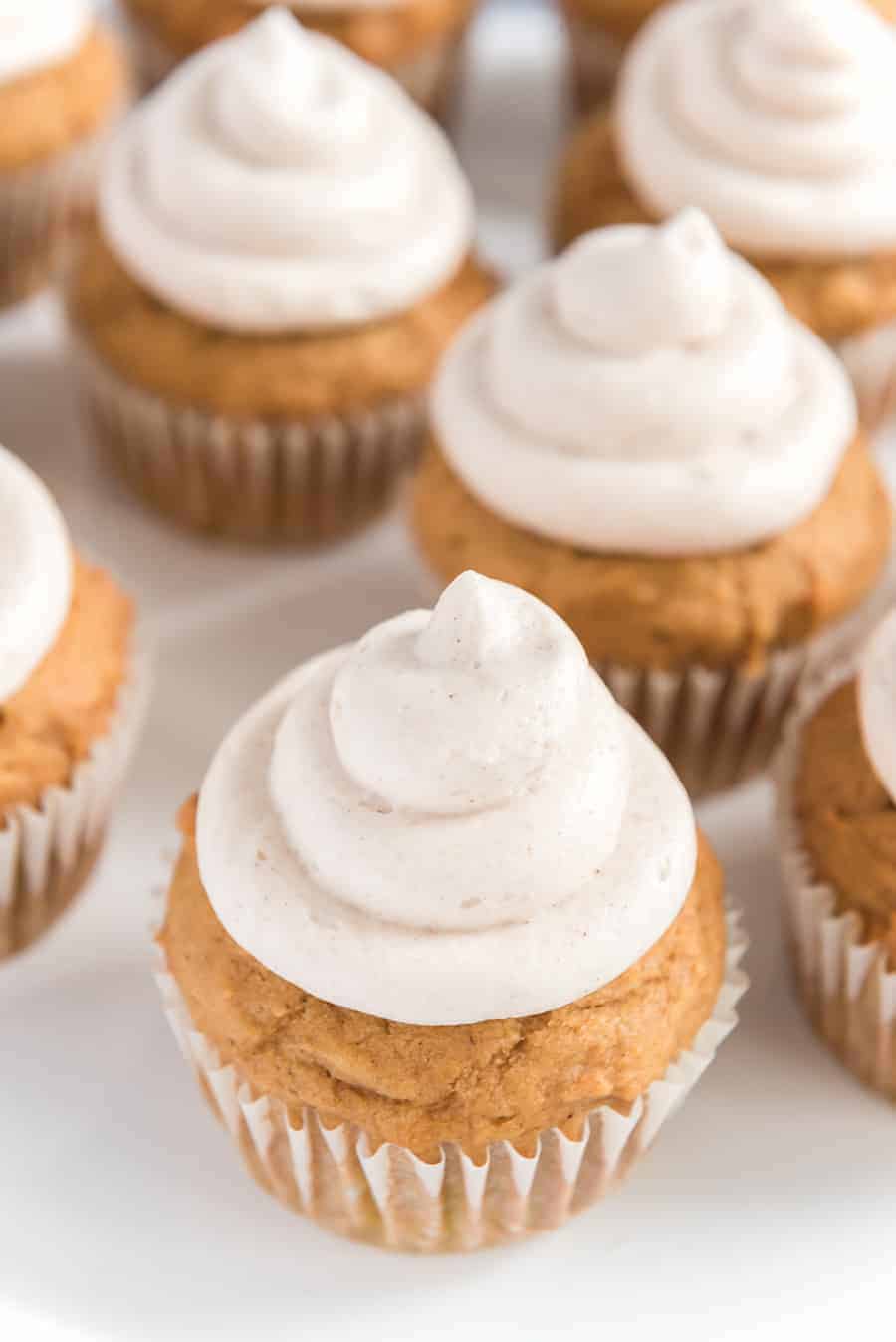 light golden pumpkin cupcakes with a cream colored and cinnamon speckled icing.