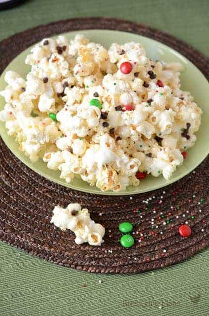 popcorn in a bowl with some chocolates and sprinkles spilling out the side of the bowl