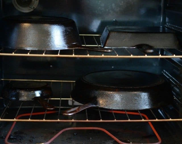 four cast iron pans turned upside down inside an oven.