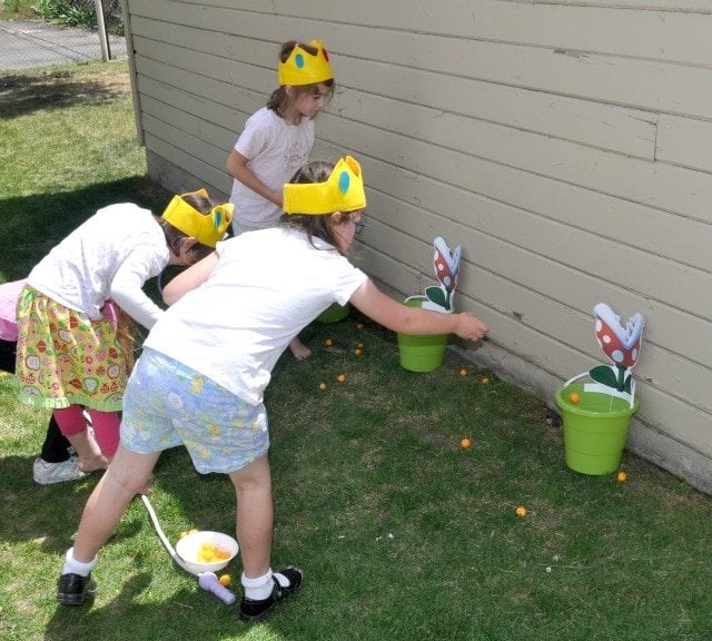 kids throwing balls into a bucket that looks like a piranha plant