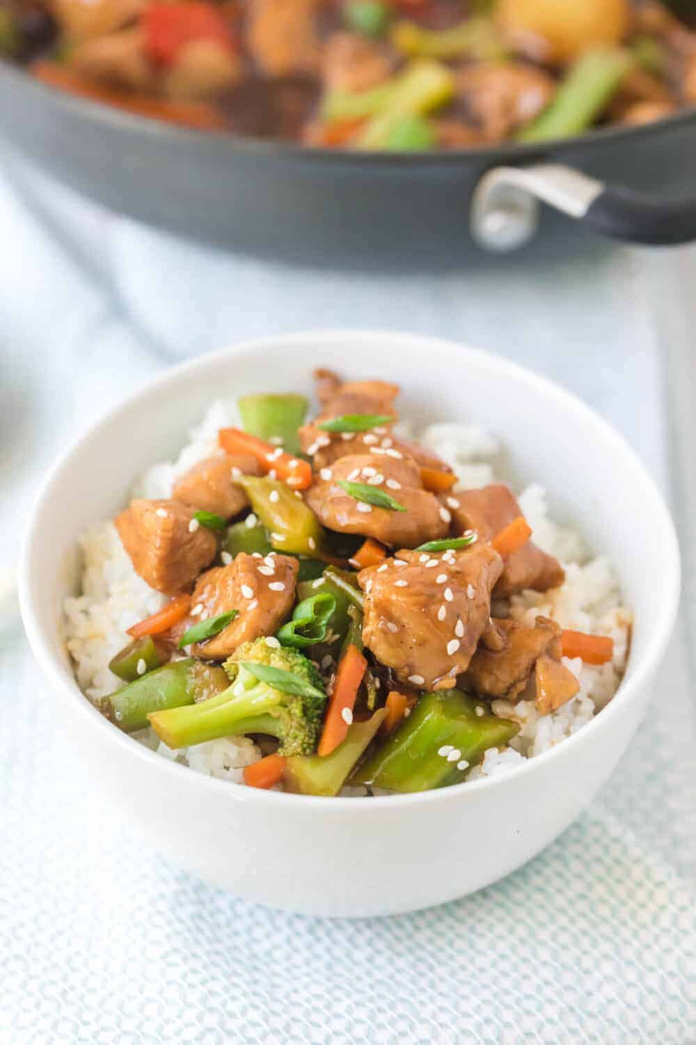 stir fry chicken and vegetables with white rice in a white bowl