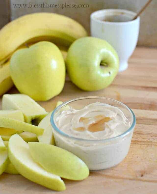 a small glass bowl of fruit dip with sliced apples and a banana sitting to the side