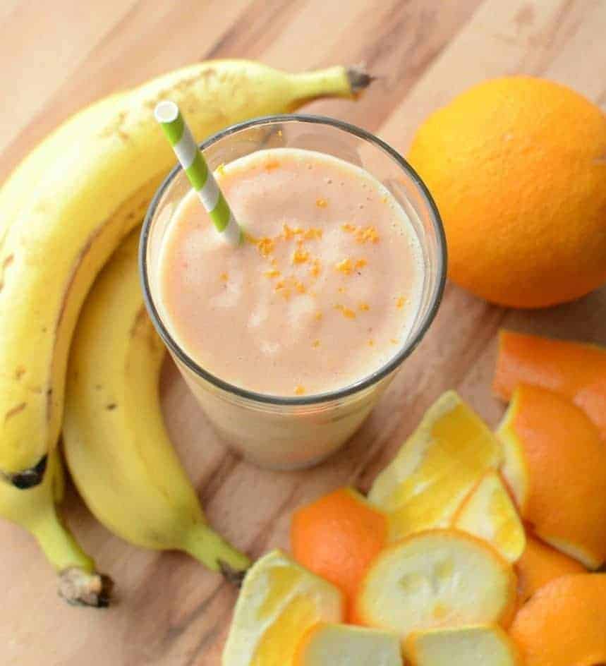 Top view of an Orange Julius smoothie in a clear glass with a straw and orange zest