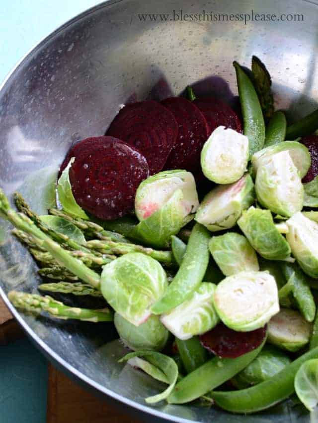 spring vegetables with oil and salt mixed together in a bowl