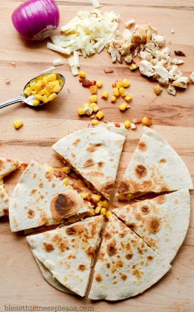 tortillas, onion, cheese, corn, and chicken on a cutting board