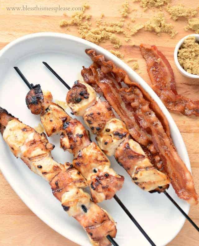 grilled skewers on a white plate with bacon and brown sugar to the side