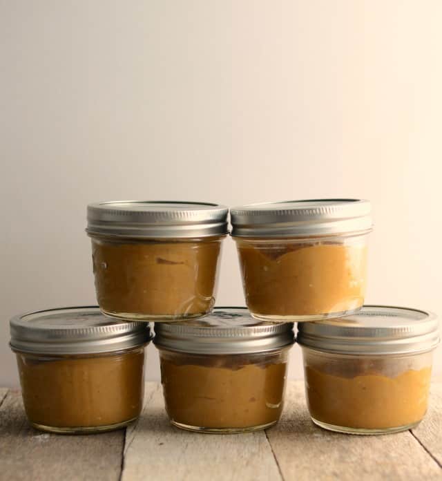 pumpkin pudding in small glass jars on wooden table.