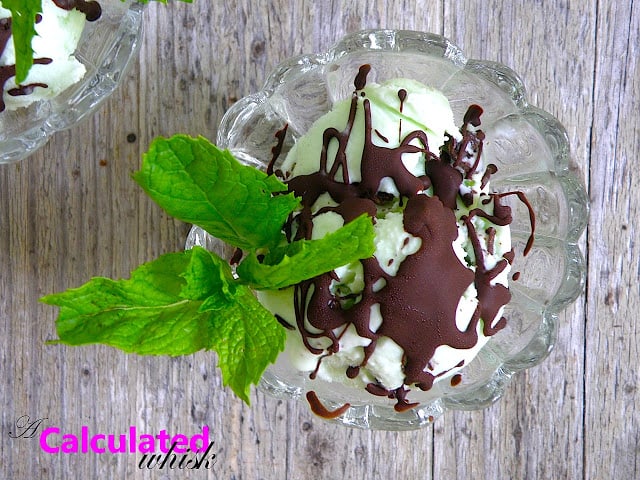 mint ice cream topped with chocolate shell and mint leaves in a glass bowl