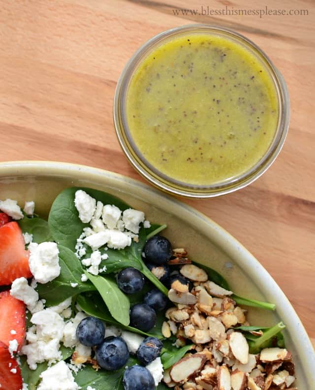 Salad in a ceramic bowl with a jar of homemade dressing to the side.