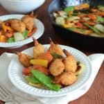Two bowls of 30 Minute Stir Fry with Crispy Shrimp with a bowl of rice and a skillet in the background