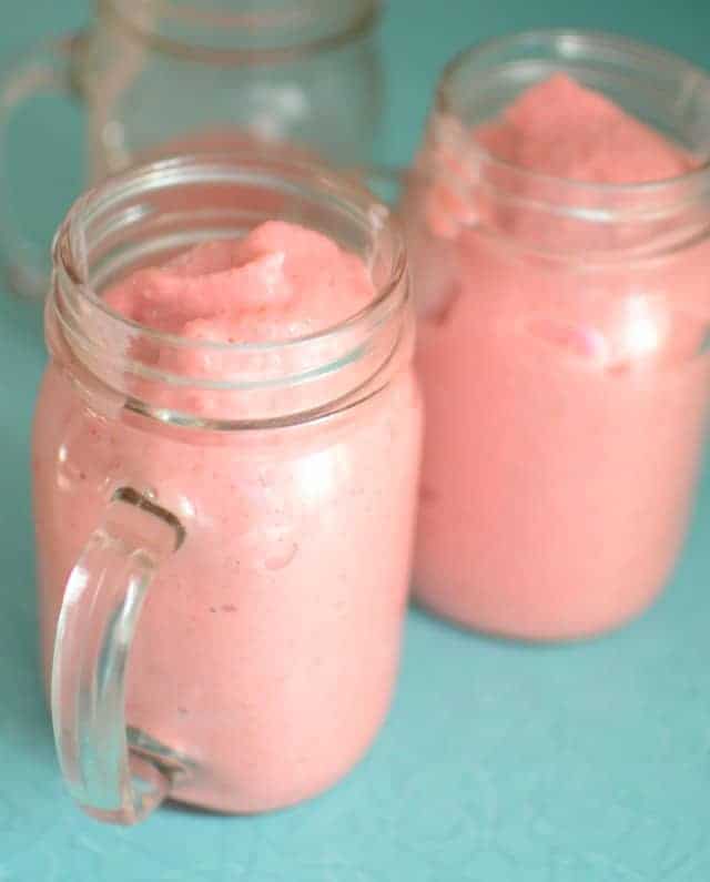 pink Guilt Free Strawberry Milkshakes in glass jar mugs on a blue countertop