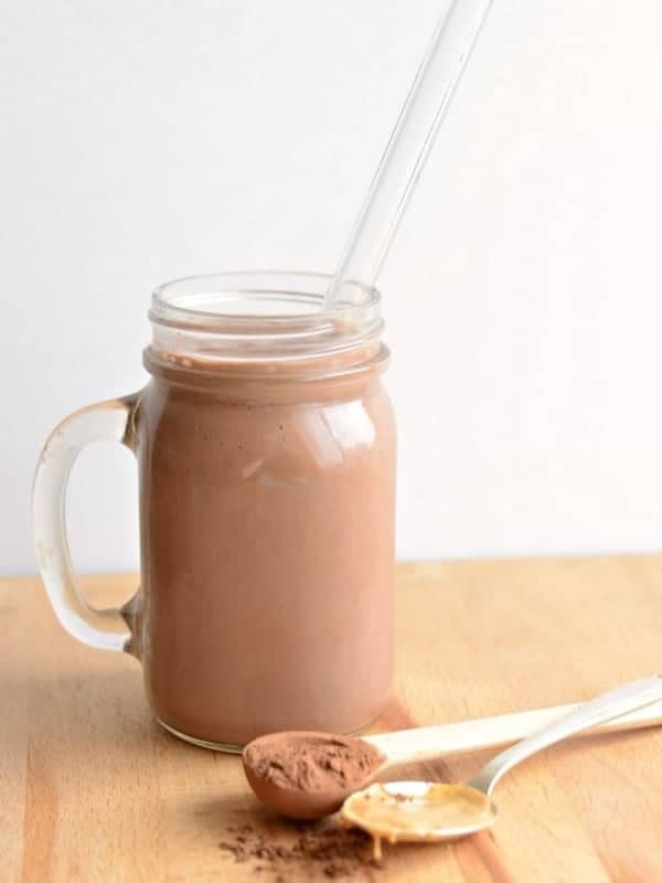 A chocolate peanut butter smoothie in a handled mason jar with a straw