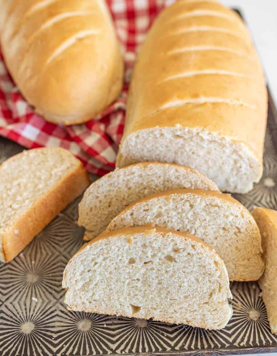 slices of french bread on metal serving tray with red and white checkered towel