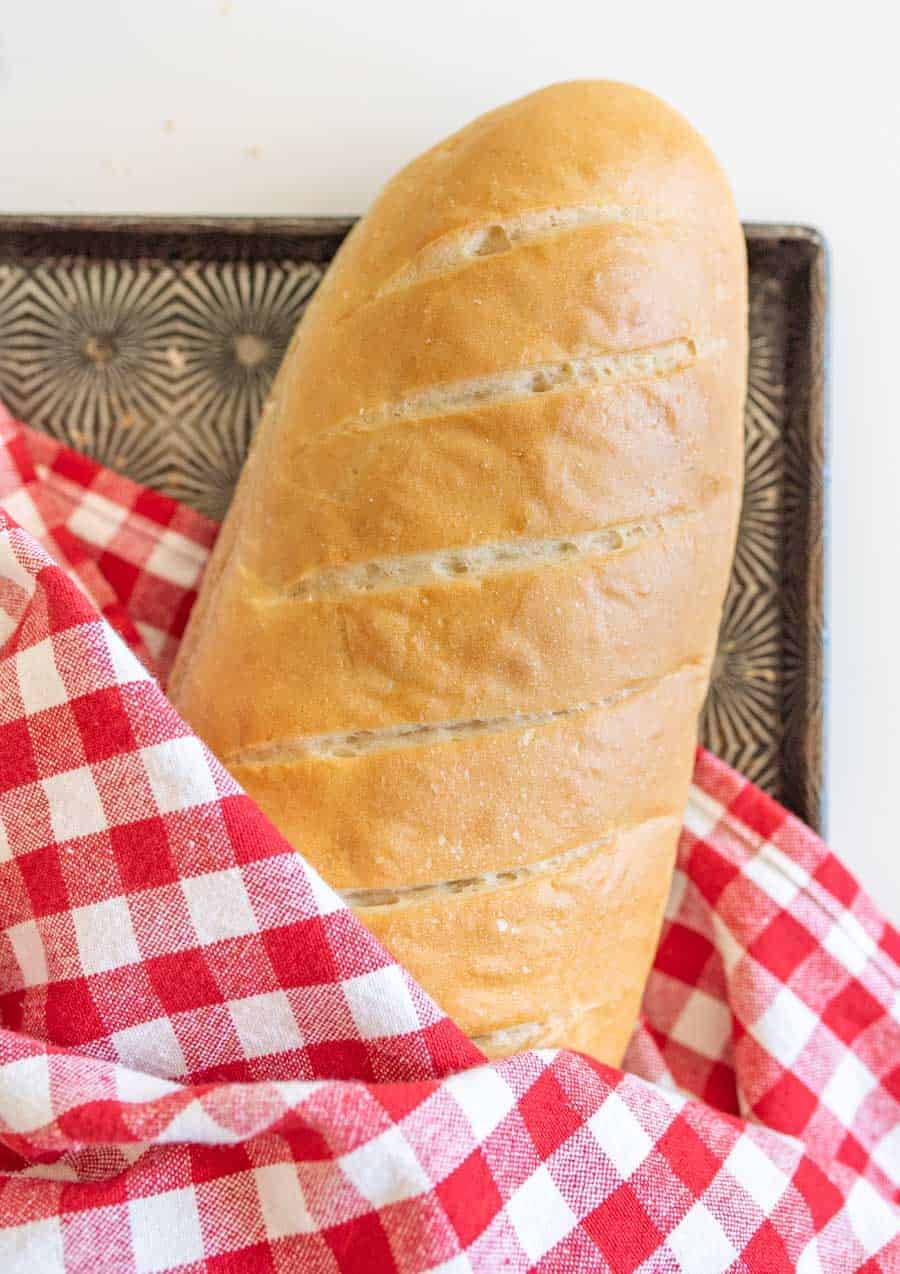 loaf of a french bread with red and white checkered towel