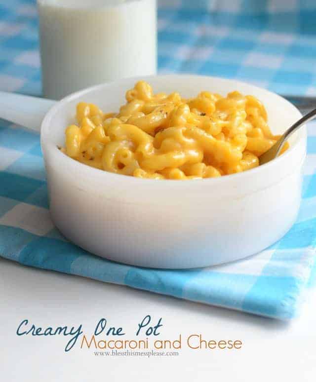 White bowl with yellow macaroni and cheese on a blue and white cloth.