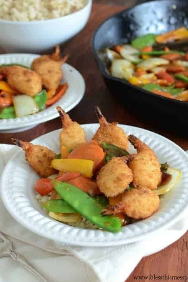 Two bowls of 30 Minute Stir Fry with Crispy Shrimp with a bowl of rice and a skillet in the background