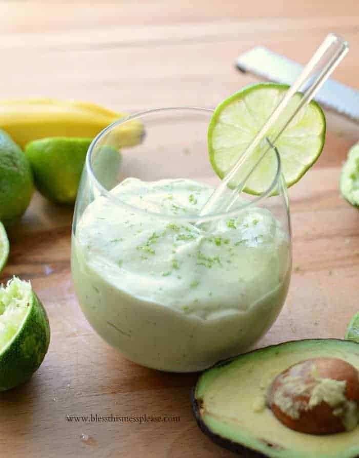 Key lime pie green smoothie in a clear glass with a straw and lime slice