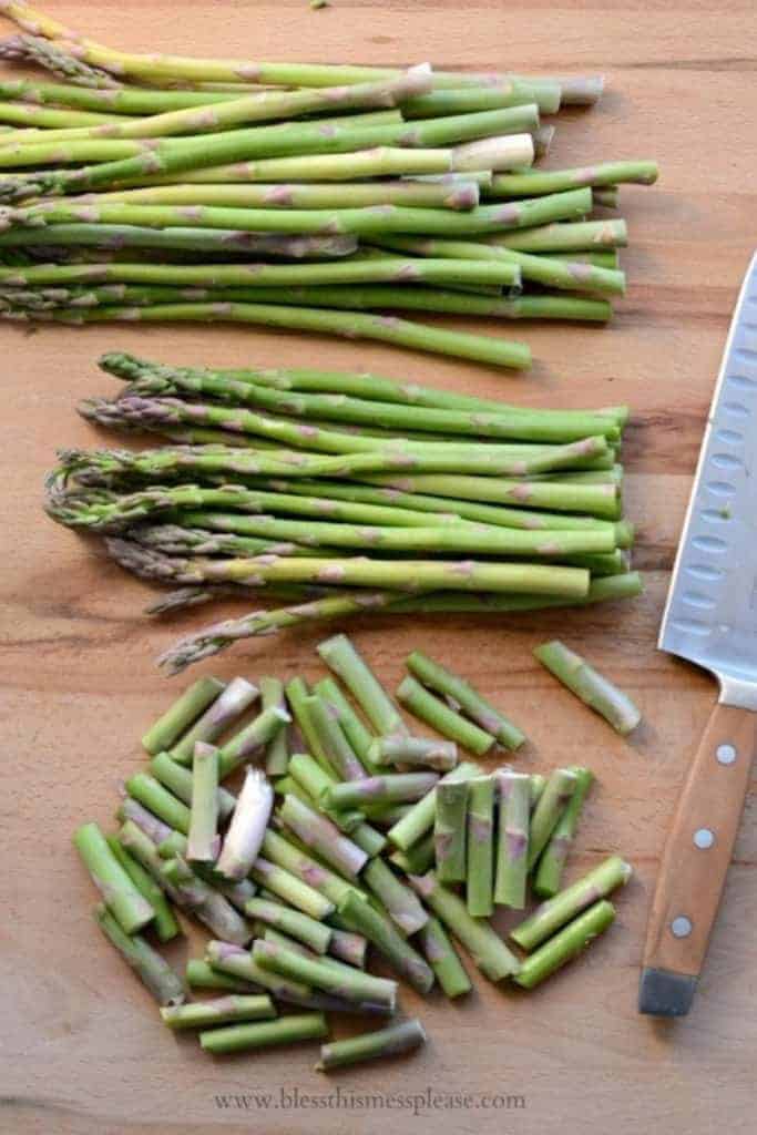 Fresh asparagus on a cutting board with ends trimmed off