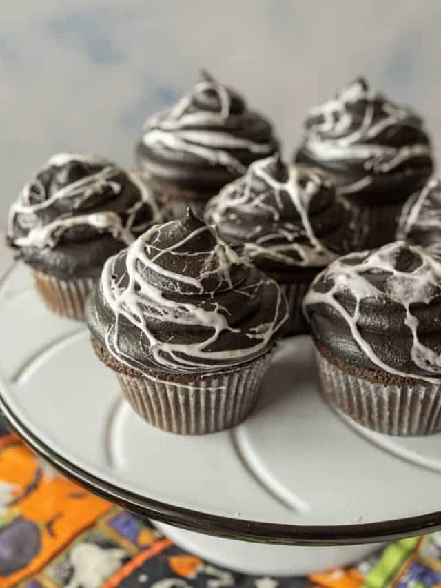 spiderweb Halloween cupcakes on a white cake stand.