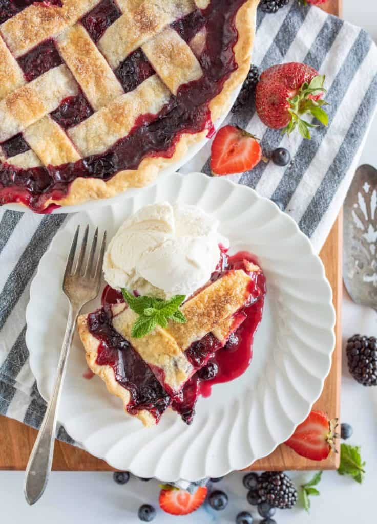 top view of a plate of tripe berry pie with ice cream next to the pie