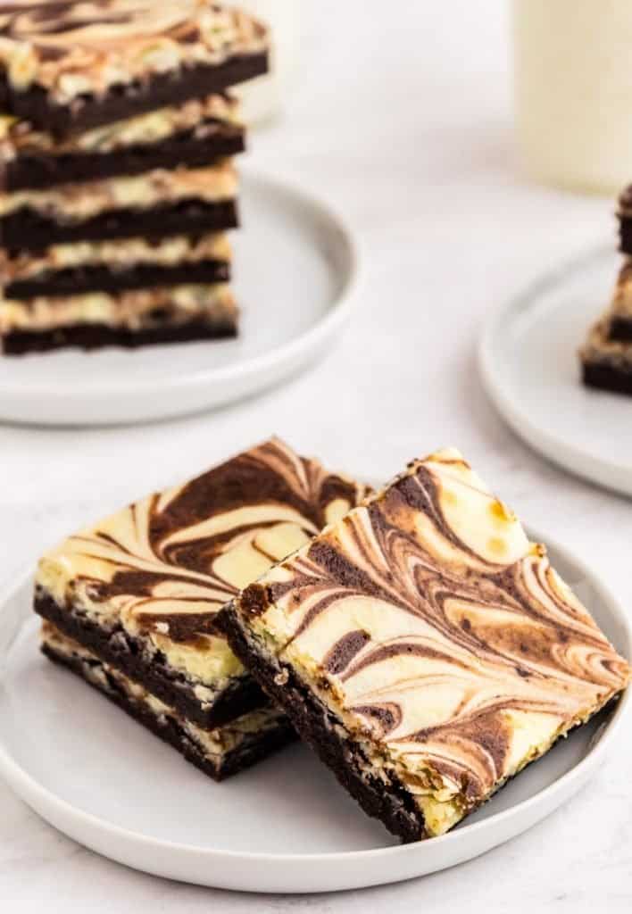slices of cheesecake brownies stacked on a plate