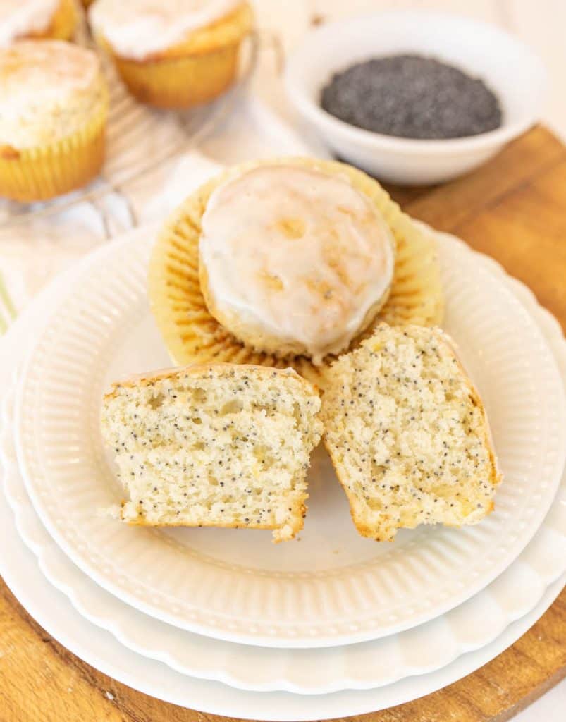 picture of a lemon poppy seed muffin cut in half and another lemon poppy seed muffin on a plate