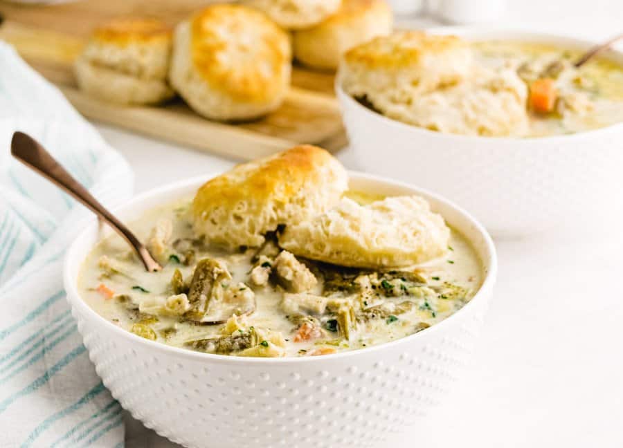 close up picture of a bowl of slow cooker chicken pot pie topped with a biscuit