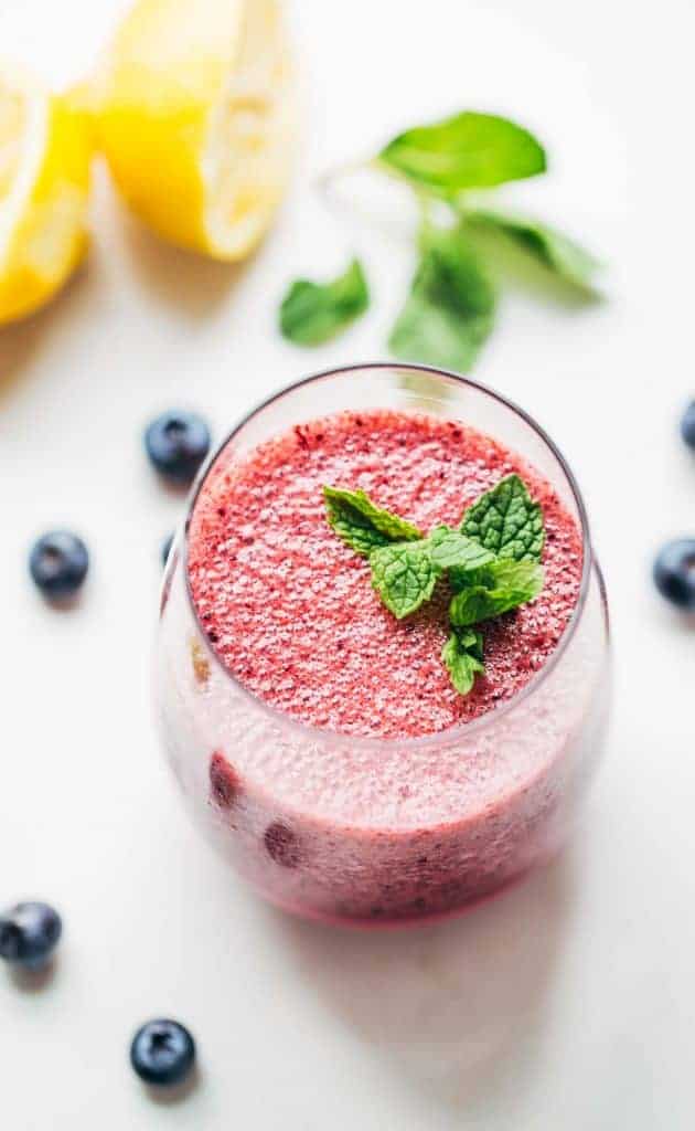 A glass of frosted blueberry lemonade with mint leaves on top