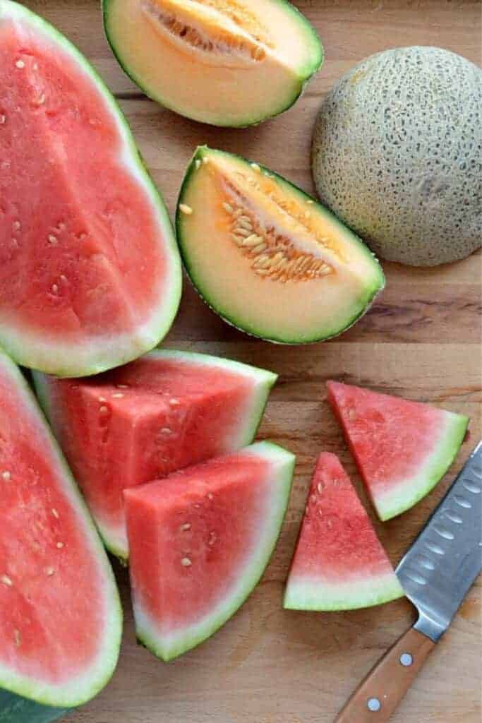 Wedges of watermelon and cantaloupe on a cutting board