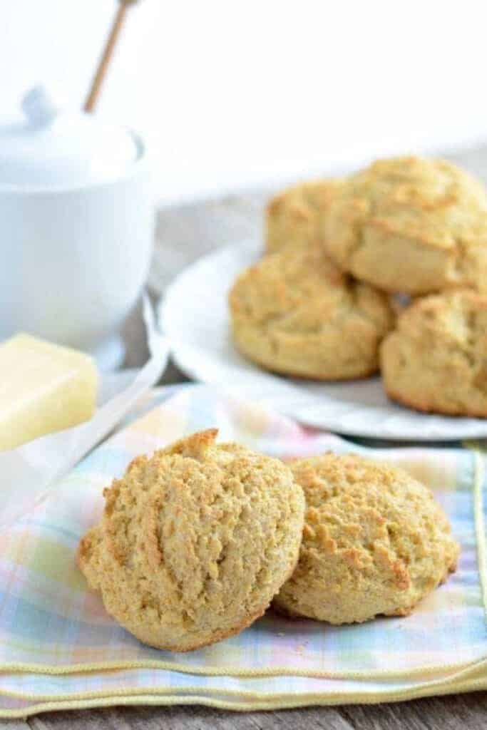 corn biscuits on a plate in front and then on a pile in a blue checkered cloth whimsical aesthetic