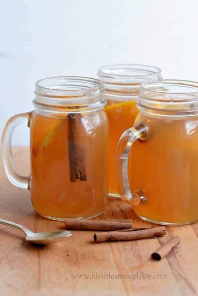 mason jars with the handle with cinnamon sticks floating in apple cider