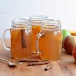 3 jars of slow cooker apple cider with fresh apples and cinnamon sticks