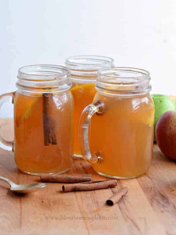3 jars of slow cooker apple cider with fresh apples and cinnamon sticks
