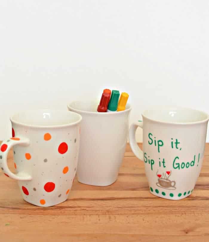 Painted Sharpie Mugs (that won't wash off!) Three painted sharpie mugs on a wooden counter.