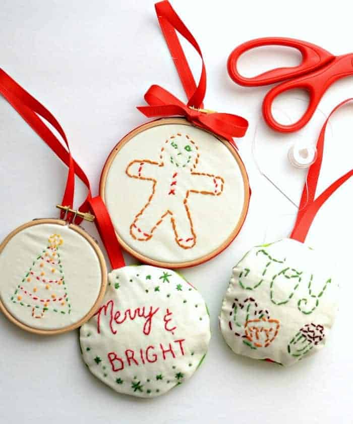 Simple Embroidered Ornaments Four embroidered Christmas ornaments - two stuffed and two in hoops, a red-handled scissors, and needle and thread.