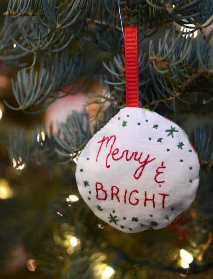Simple Embroidered Ornaments Stuff embroidered ornament that says merry and bright hanging on a Christmas tree.