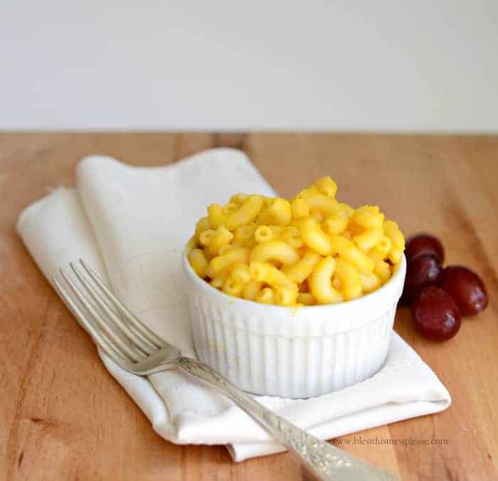 macaroni and cheese in a small white bowl with a napkin and fork to the side