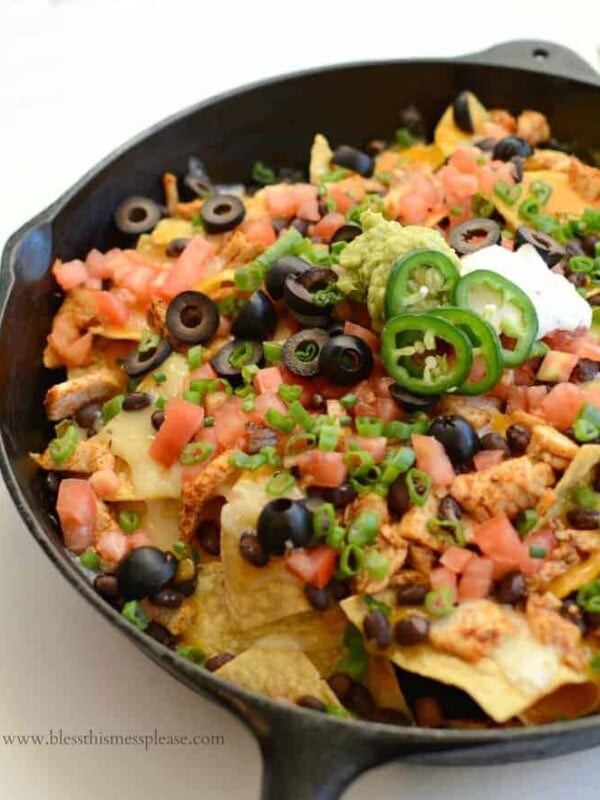 Skillet of chicken nachos with peppers, tomatoes, olives, and more