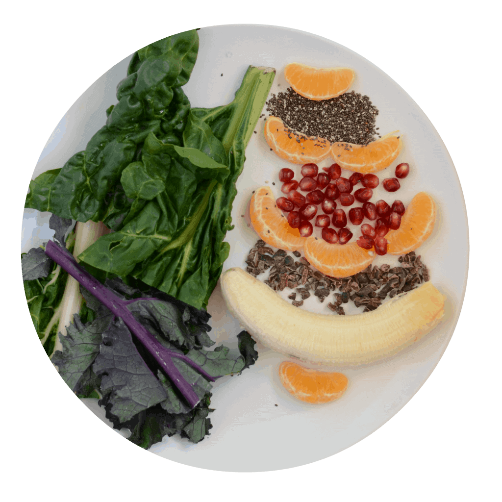 banana, oranges,pomegranate, chia seeds, and greens on a plate