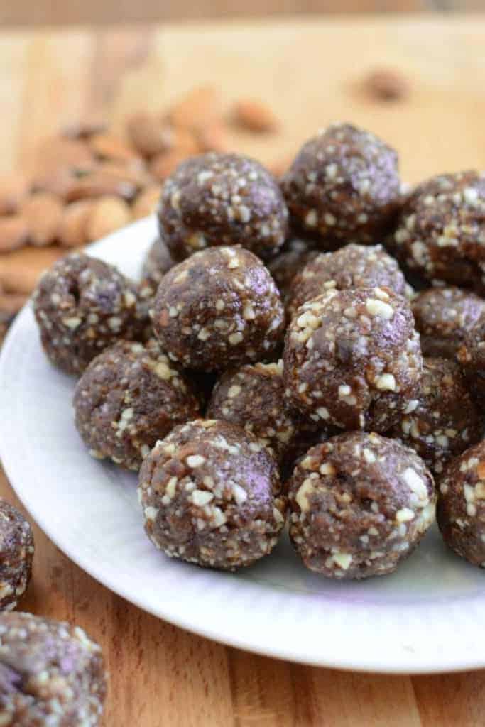 A plate of cherry energy balls with chopped nuts