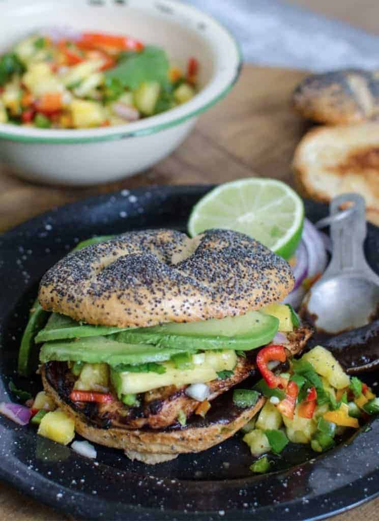 Grilled chicken sandwich with pineapple salsa and avocado, on a poppy-seed bun