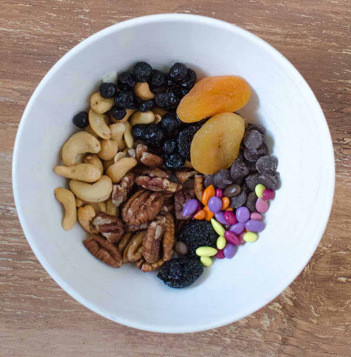 Trail Mix - kuivatut kirsikat, kuivatut mustikat, kuivatut aprikoosit, cashewpähkinät, pekaanipähkinät, tummat suklaalastut ja karkkipäällysteiset auringonkukansiemenet.