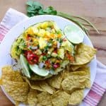 top view of pineapple salsa and lime stacked into a pineapple rind with tortilla chips
