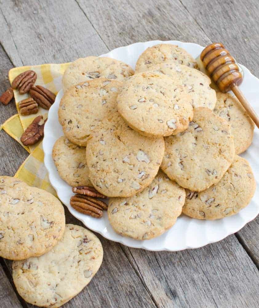 cookies on a white plate with pecans to the side on a wooden background