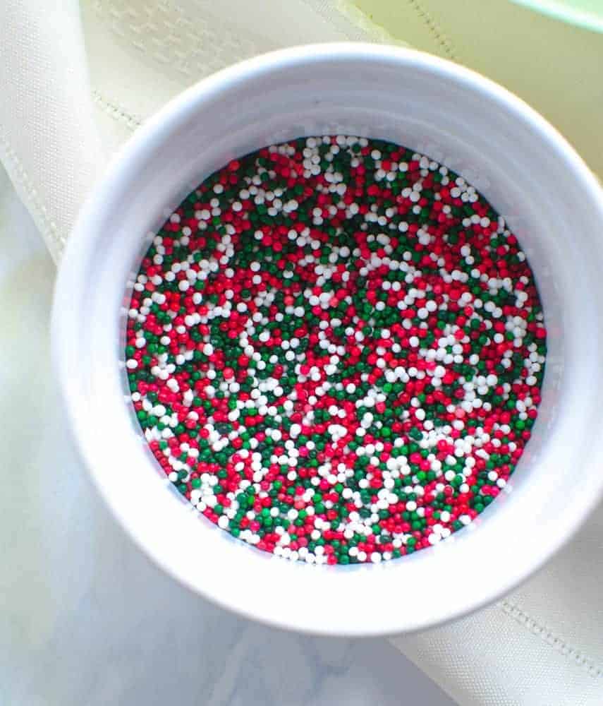 Sprinkles Red, green, and white small sphere-shaped sprinkles in a white bowl.