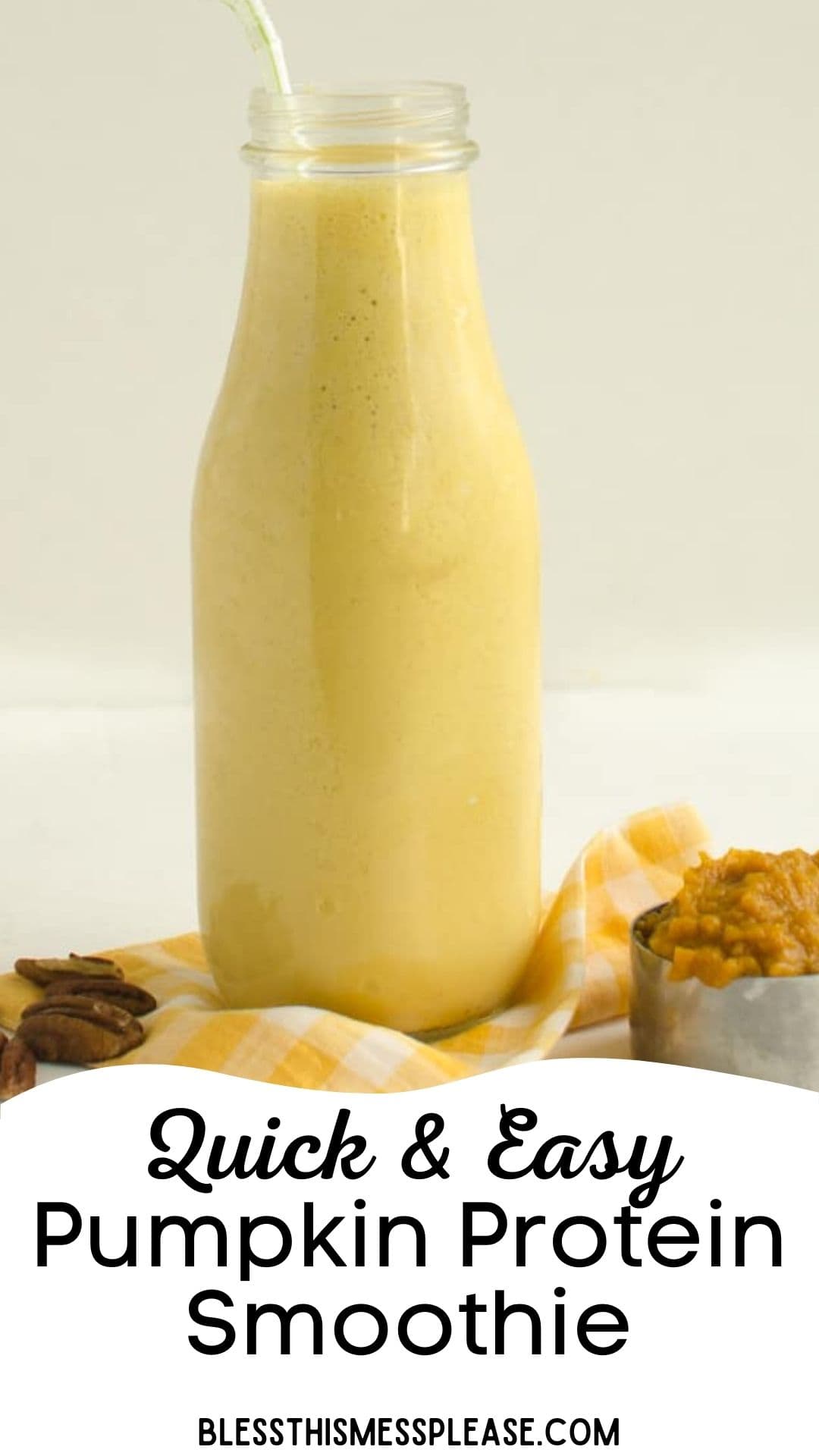 A clear glass bottle filled with a creamy, light orange Healthy Pumpkin Protein Smoothie sits on a yellow checkered cloth, next to a small metal bowl of pumpkin puree and some pecans. Text reads: “Quick & Easy Pumpkin Protein Smoothie.”.