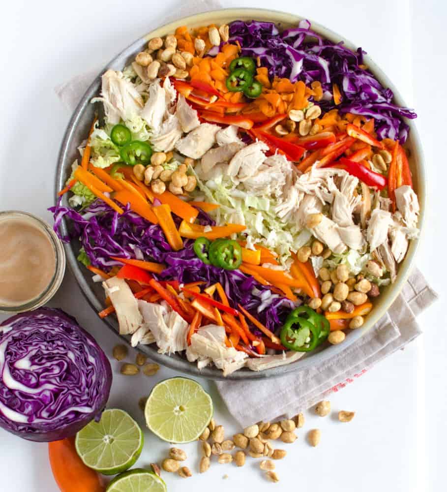 A bowl of colorful Asian Chicken Salad and a bowl of Peanut Lime Dressing