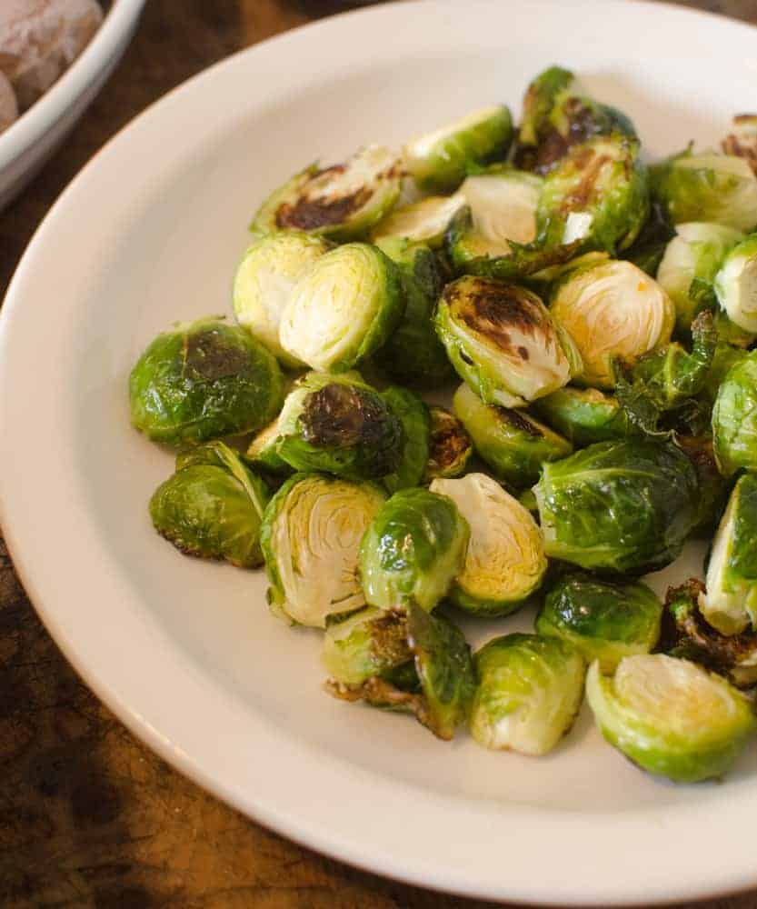 Five Ingredient Sides - Brussels Sprouts Roasted Brussels sprouts on a white plate.