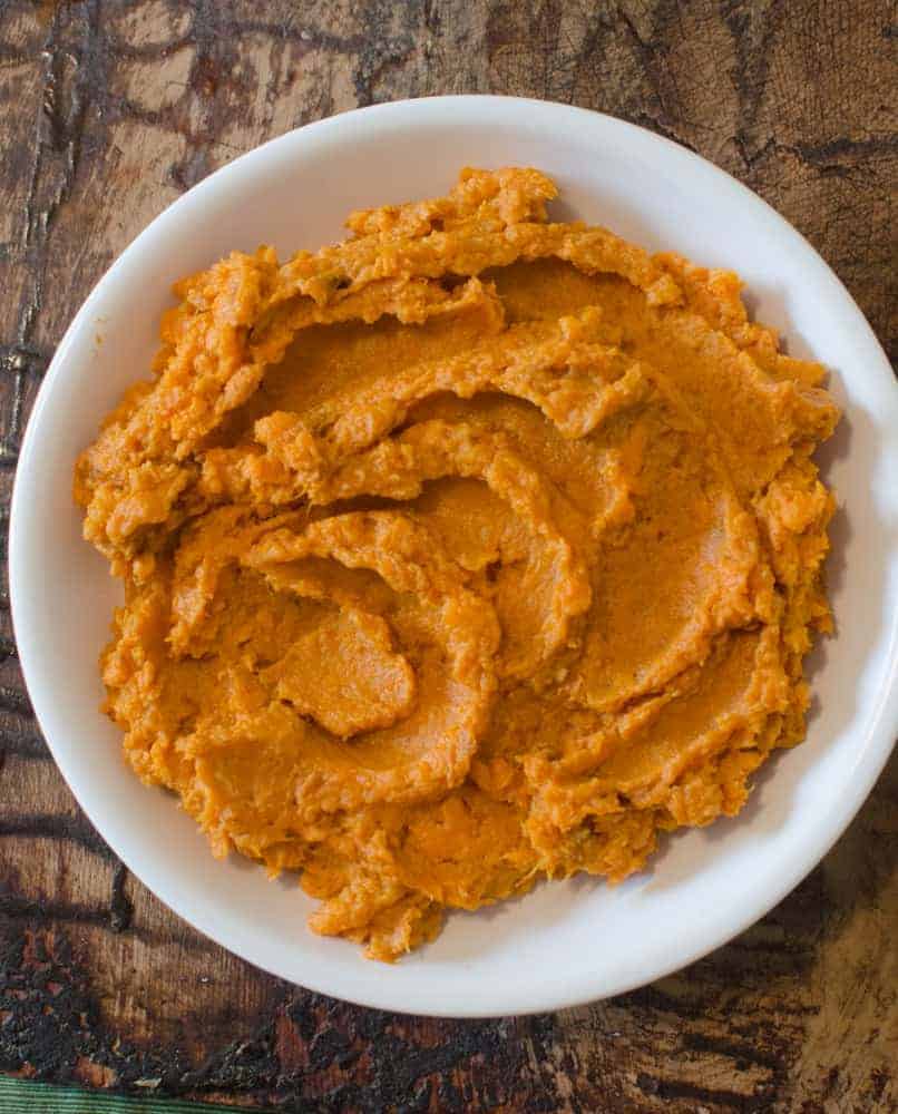 Five ingredient sides will save you time on Thanksgiving - and there are 8 easy recipes for them here! Bonus: everything is easily made vegan/gluten-free Mashed roasted sweet potatoes in a white bowl on a wooden table.